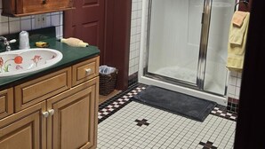 A bathroom with a wooden vanity, a glass shower enclosure, and a tiled floor with a checkered pattern. - Historic Farnsworth House Inn (Gettysburg)