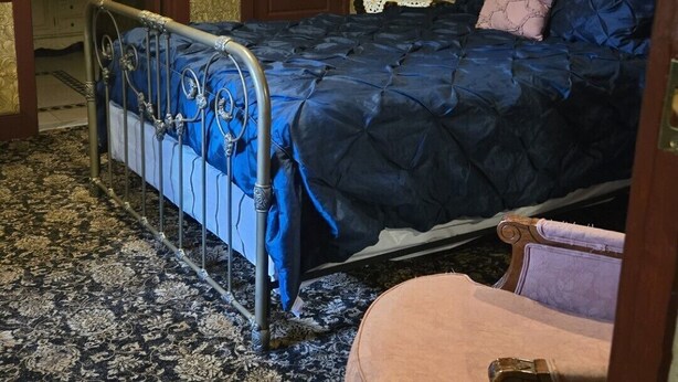 A bedroom with a bed, a chair, a chandelier, and a door. - Historic Farnsworth House Inn (Gettysburg)