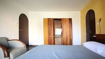A hotel room with a bed, a chair, and a wardrobe with a mirror.