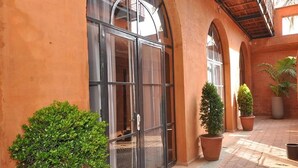 A courtyard with a glass door, potted plants, and a tiled floor. - Hôtel Le Djoloff (Dakar)