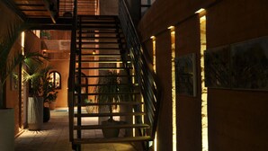 A staircase in a building with warm lighting and potted plants. - Hôtel Le Djoloff (Dakar)