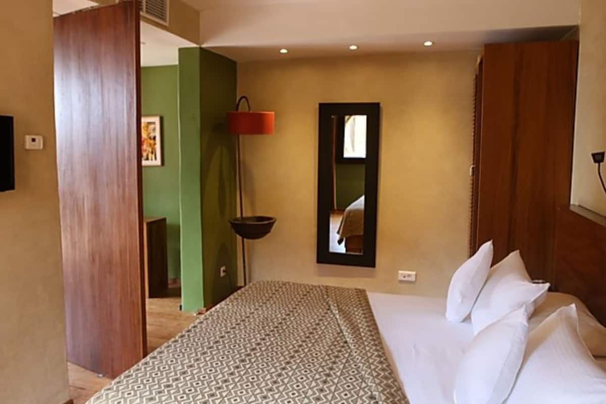 A hotel room with a bed, a mirror, a television, and a door.