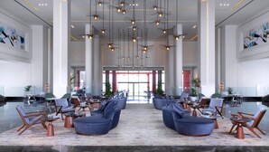 Un hall d’entrée spacieux, doté de mobilier moderne, de grandes fenêtres et d’un plafond haut orné de luminaires suspendus.
