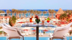 Une table avec des boissons et un vase, donnant sur une piscine et une plage.