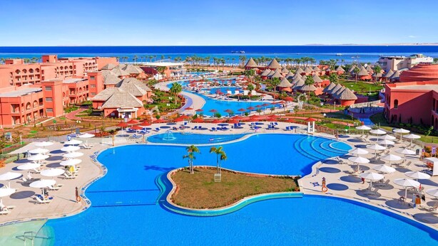Un complexe hôtelier doté de plusieurs piscines, de palmiers et offrant une vue sur la plage.