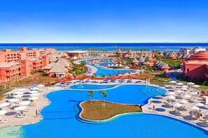 Ein Resort mit mehreren Schwimmbecken, Palmen und Blick auf den Strand.