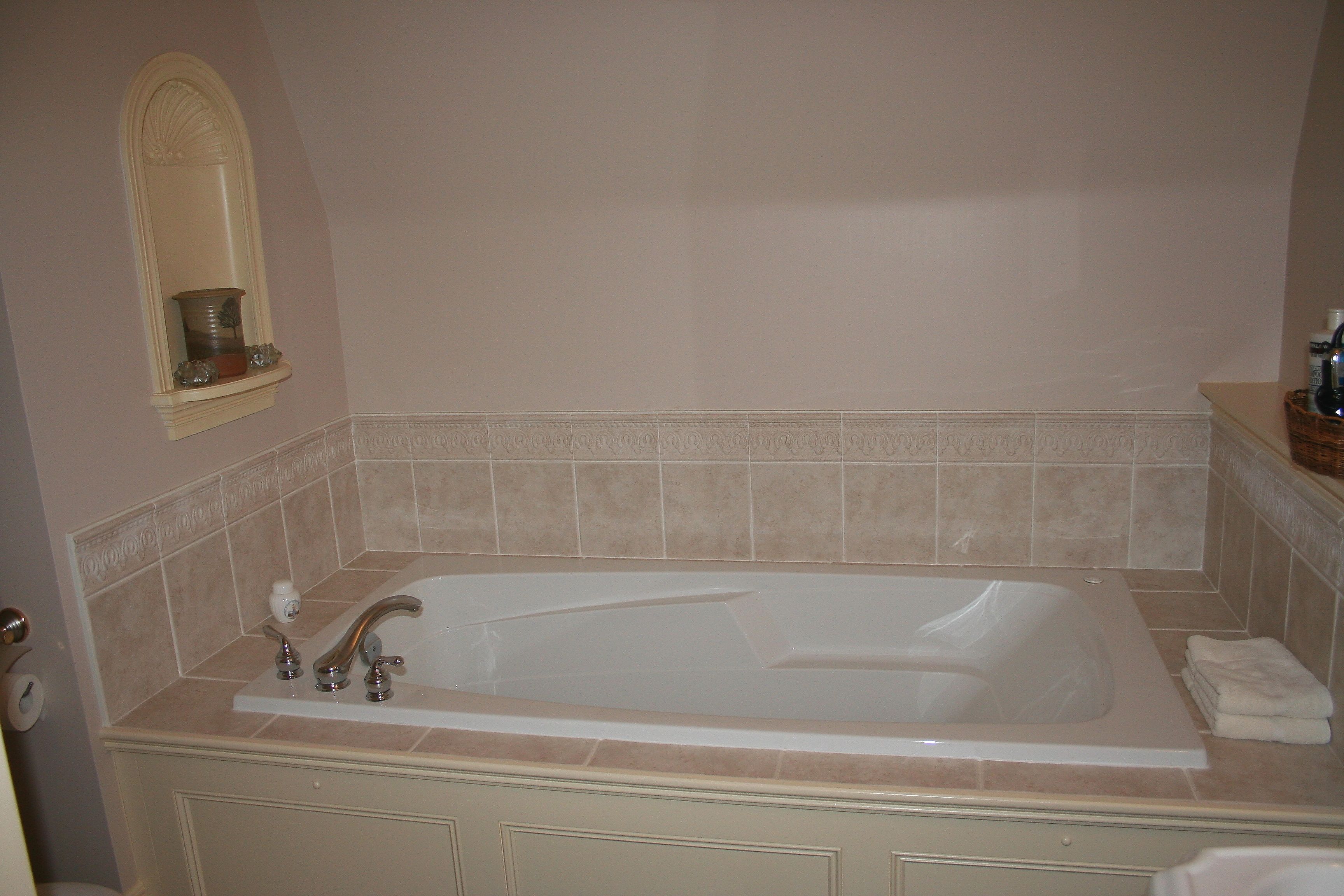A bathroom with a large bathtub, a mirror, and a towel rack.