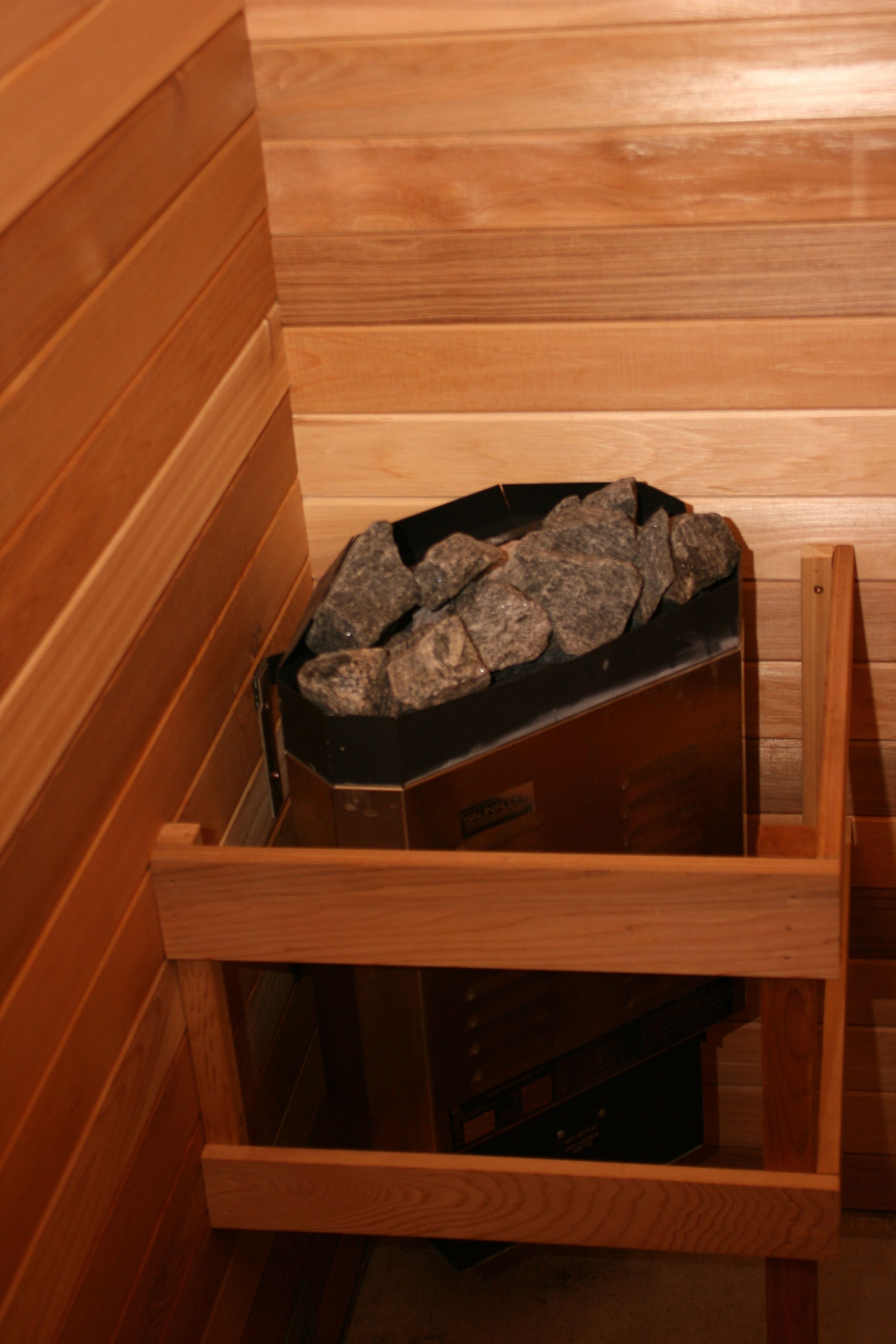 A sauna with wooden walls and a stone-filled basin.