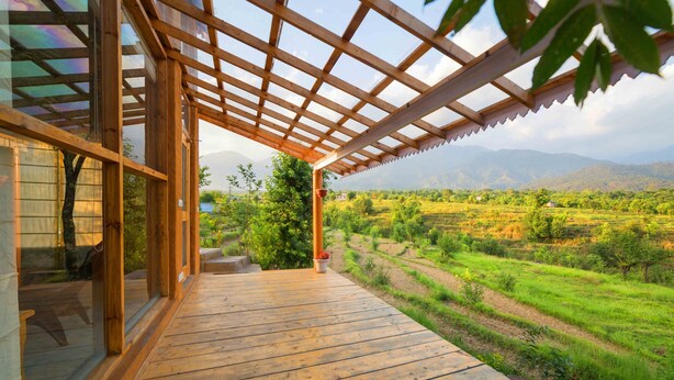 Una terraza de madera con vistas a campos escalonados y montañas.