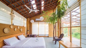 Una habitación con una cama de madera, una mesa, sillas y vistas al verdor exterior.