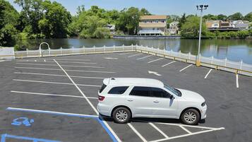 Un parking avec un VUS blanc, des places délimitées et une clôture blanche.