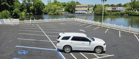 A parking lot with a white SUV, marked spaces, and a white fence.
