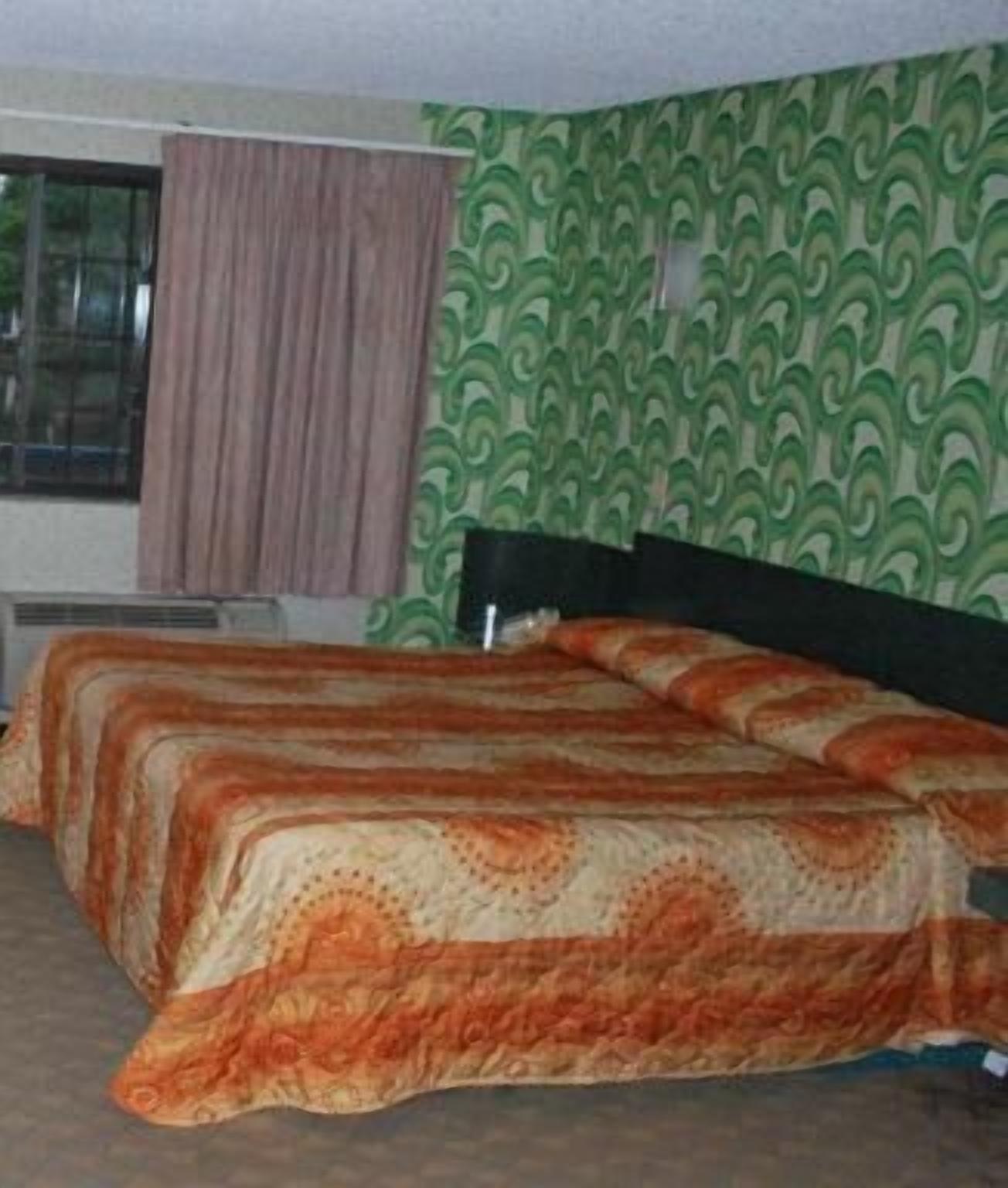 A room with a bed, a window with curtains, and a patterned wall.