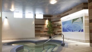 A spa area with a hot tub, a potted plant, and a mural on the wall. - Manoir du Lac William (St-Ferdinand)