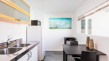 Una cocina compacta con un lavamanos doble, un refrigerador, un microondas y un comedor con dos sillas y una mesa.