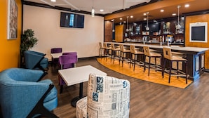Una zona de bar con mostrador, taburetes y un televisor montado en la pared.