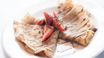 A plate of crepes with chocolate sauce and strawberries.