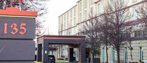 A building with a sign displaying the number 135, a covered entrance, and a parking area.