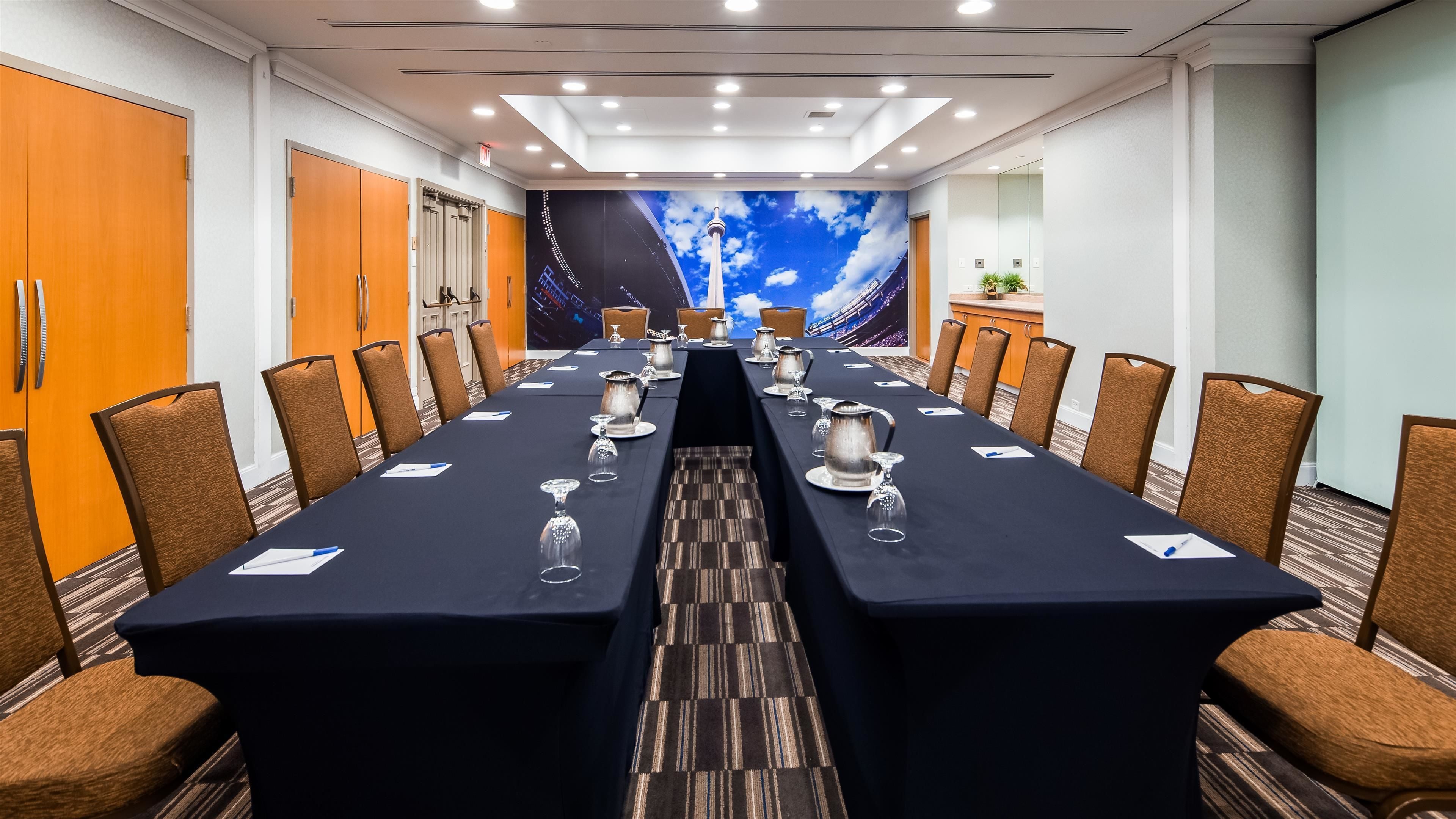A conference room with a long table, chairs, and a large mural of a city skyline.