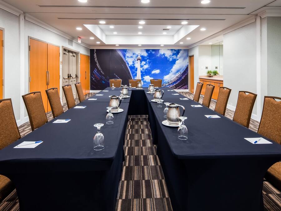A conference room with a long table, chairs, and a large mural of a city skyline.