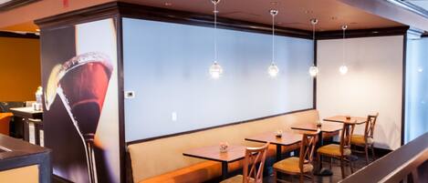A restaurant with wooden tables and benches, pendant lights, and a large poster on the wall.