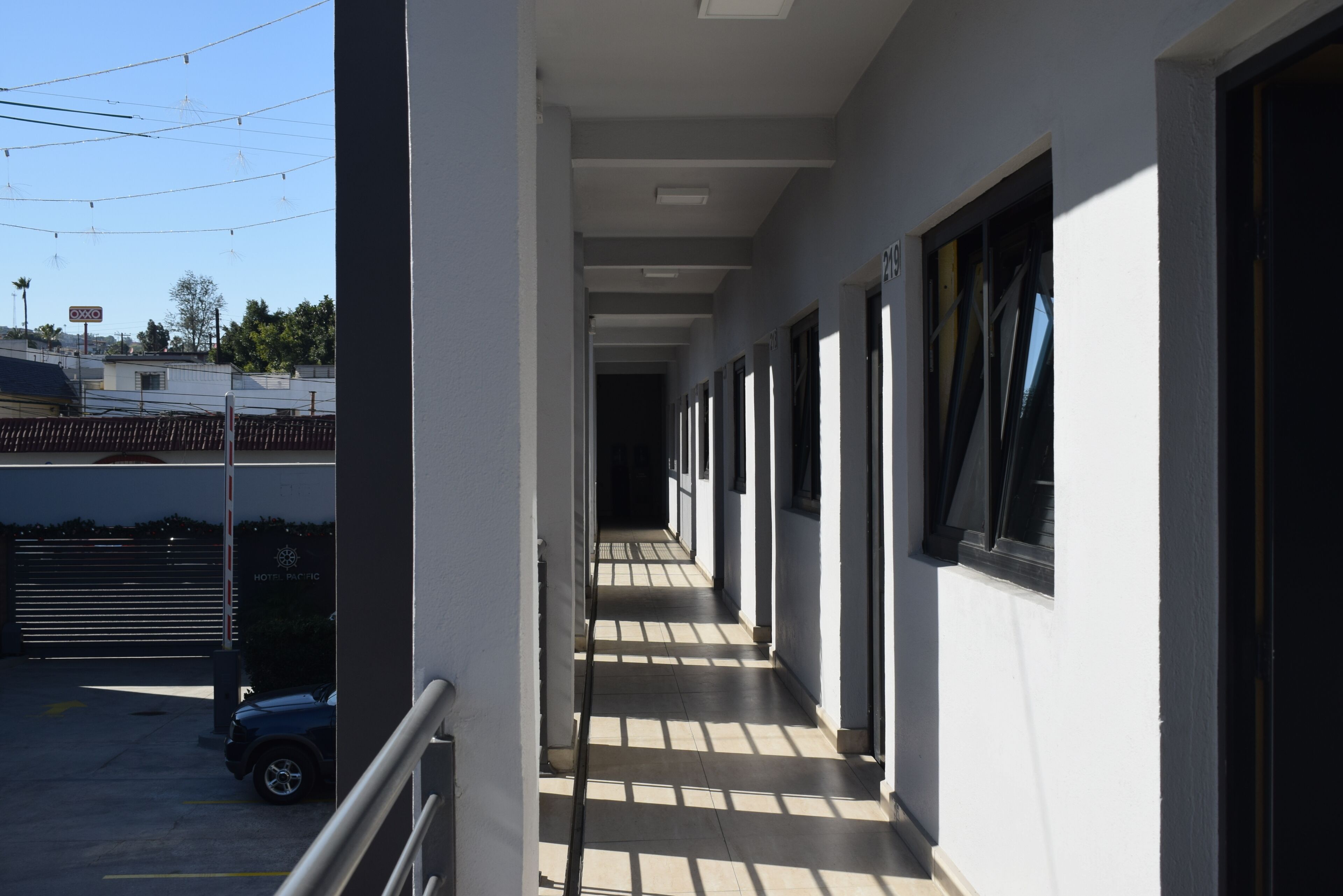 Un couloir d’hôtel offrant une vue dégagée sur le ciel et donnant sur une voiture garée à l’extérieur.