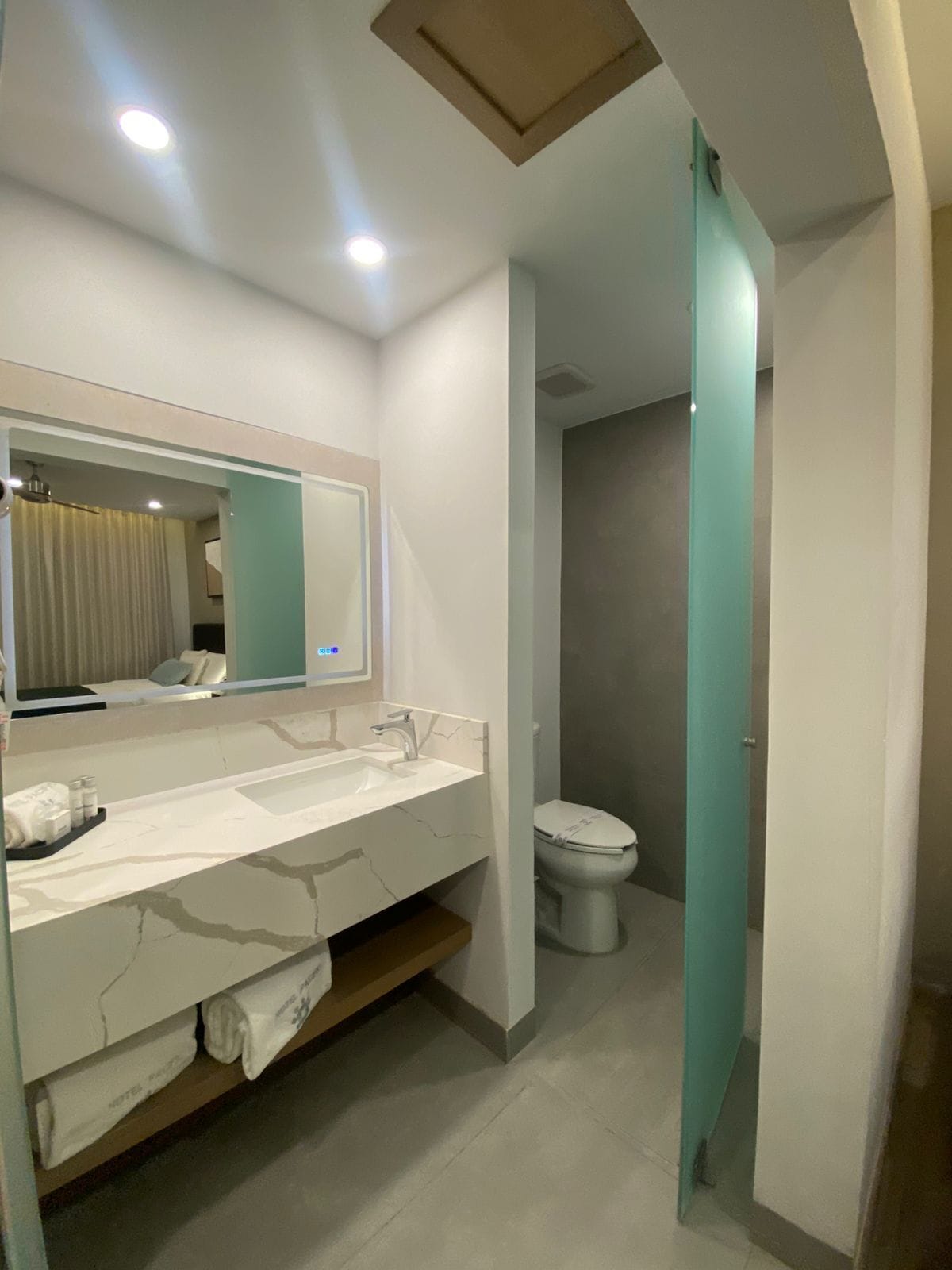 A modern bathroom with a white vanity, a mirror, and a toilet.