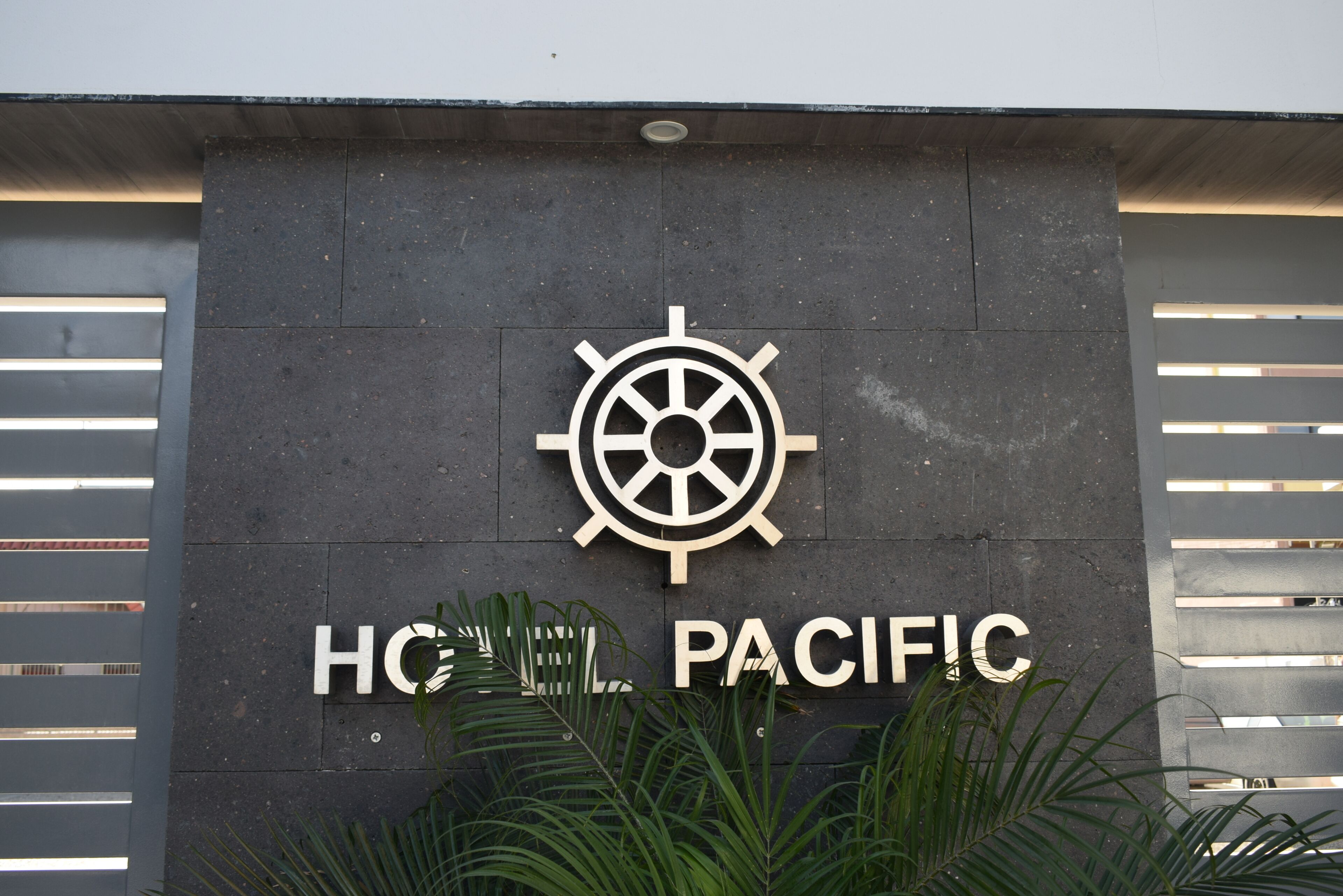 Un letrero con el logotipo de una rueda de barco y el texto "HOTEL PACIFIC".