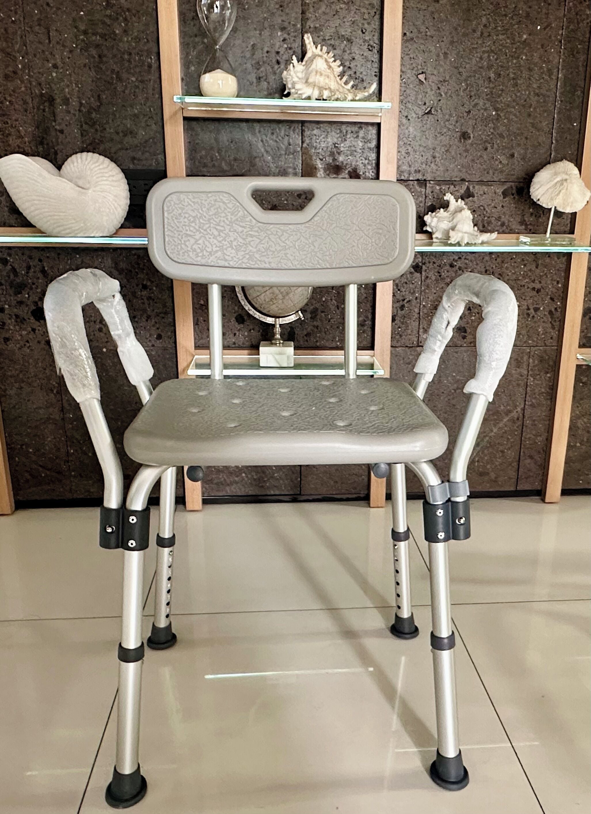A chair with a padded seat and backrest, adjustable armrests, and a base with wheels.