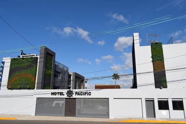 A modern hotel with a large sign reading "HOTEL PACIFIC" and a garage door. - Hotel Pacific (Tijuana)