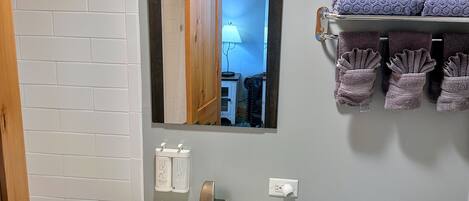Un baño con un lavamanos blanco, un inodoro, un espejo y un perchero con toallas.