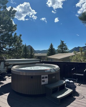 A hot tub on a wooden deck with a view of mountains and trees. - Columbine Inn (Estes Park)