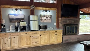 Una cocina amplia con armarios de madera, microondas integrado, refrigerador y chimenea de piedra.