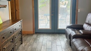 Una habitación con un aparador de madera, un sofá de cuero y un doble vano con paneles de vidrio.