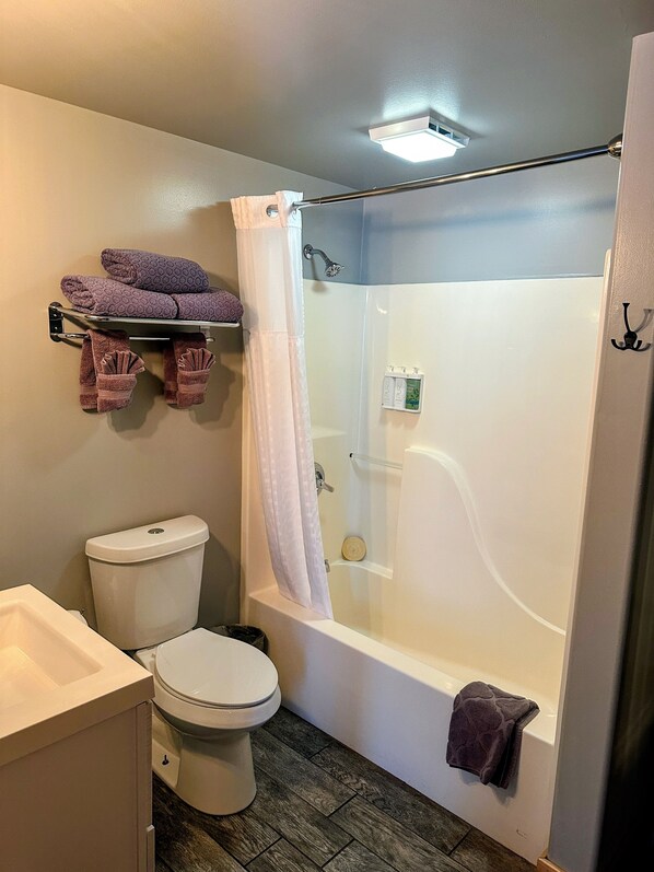 A bathroom with a toilet, a bathtub, a shower curtain, and a towel rack.