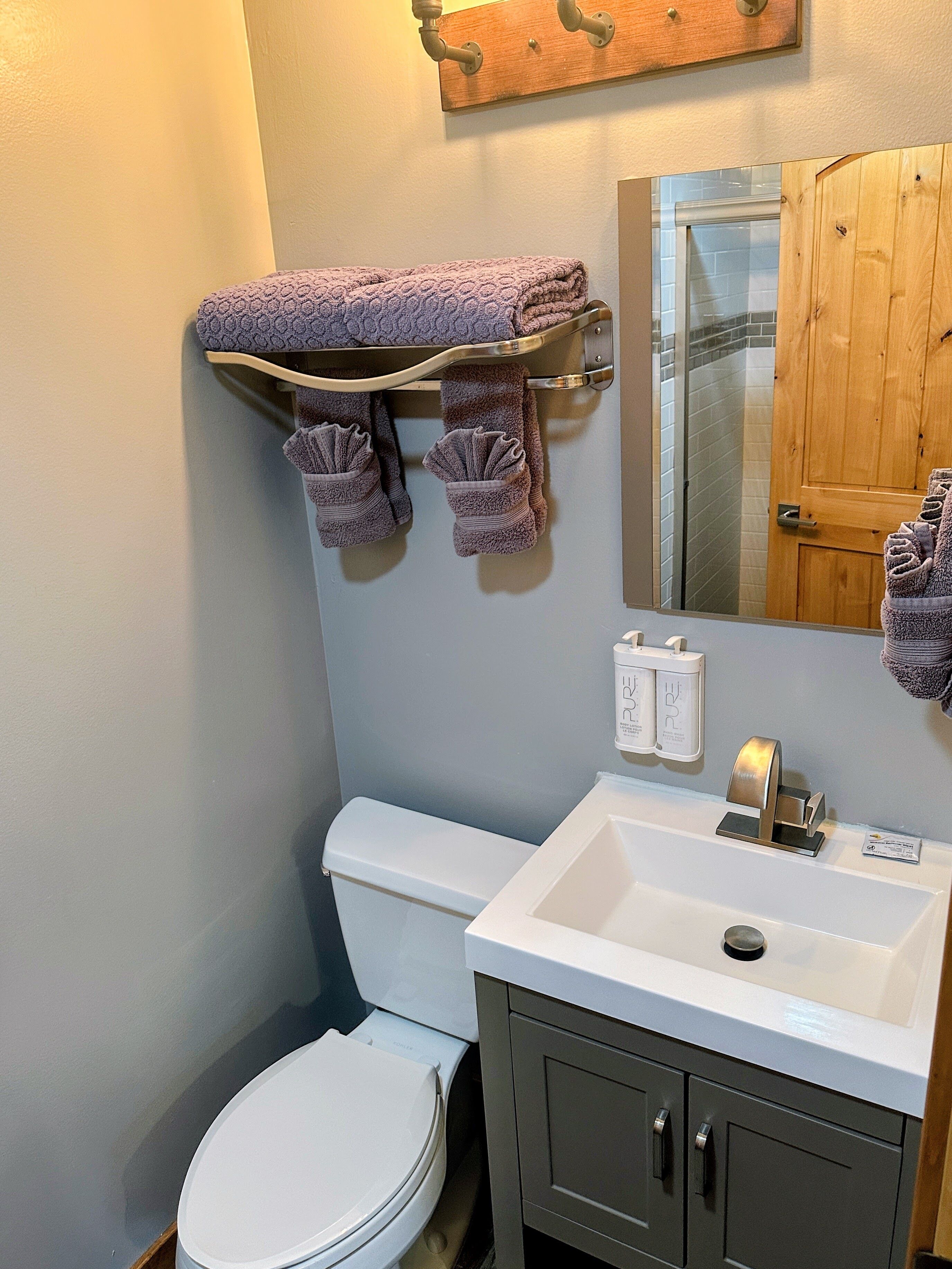 Un baño con inodoro, lavamanos y perchero para toallas.