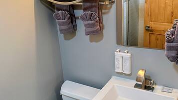 Un baño con inodoro, lavamanos y perchero para toallas.