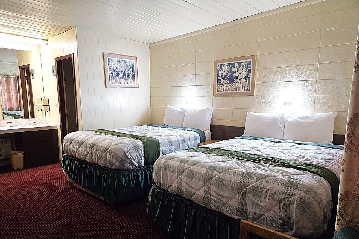 Une chambre d’hôtel avec deux lits, une salle de bain et un miroir.
