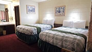 A hotel room with two beds, a bathroom, and a mirror.