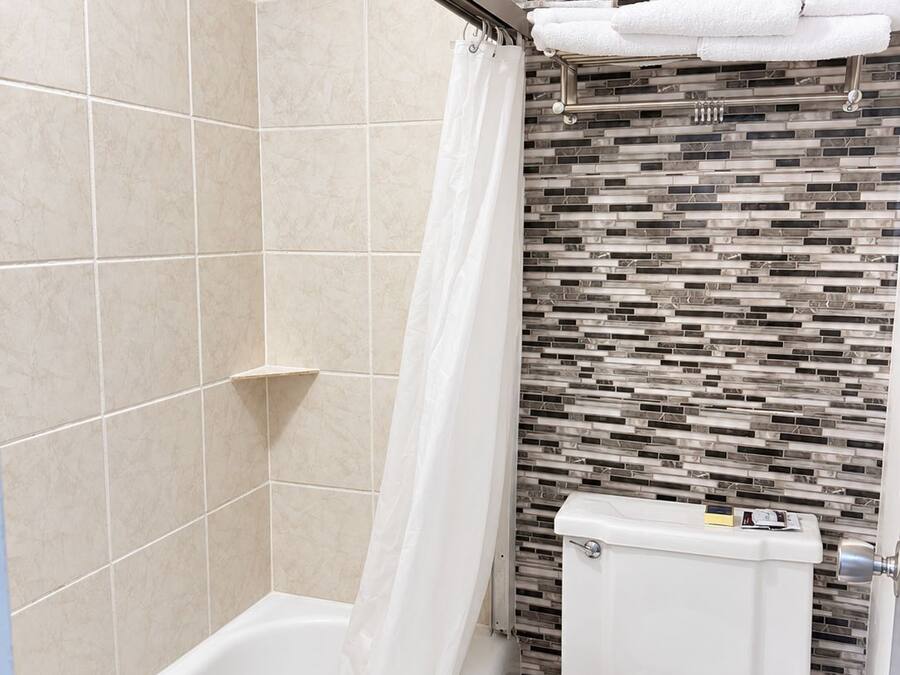 Un baño con bañera, inodoro y cortina de ducha.