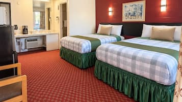 A hotel room with two beds, a desk, and a kitchenette.