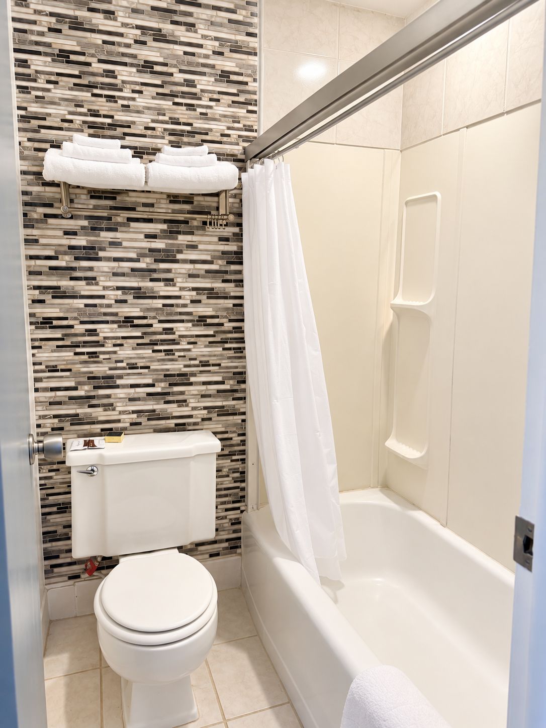 Un bagno con il water, una doccia con porta in vetro e una parete rivestita in piastrelle.