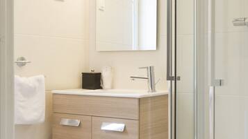 A modern bathroom with a glass shower enclosure, a wooden vanity, and a white toilet.
