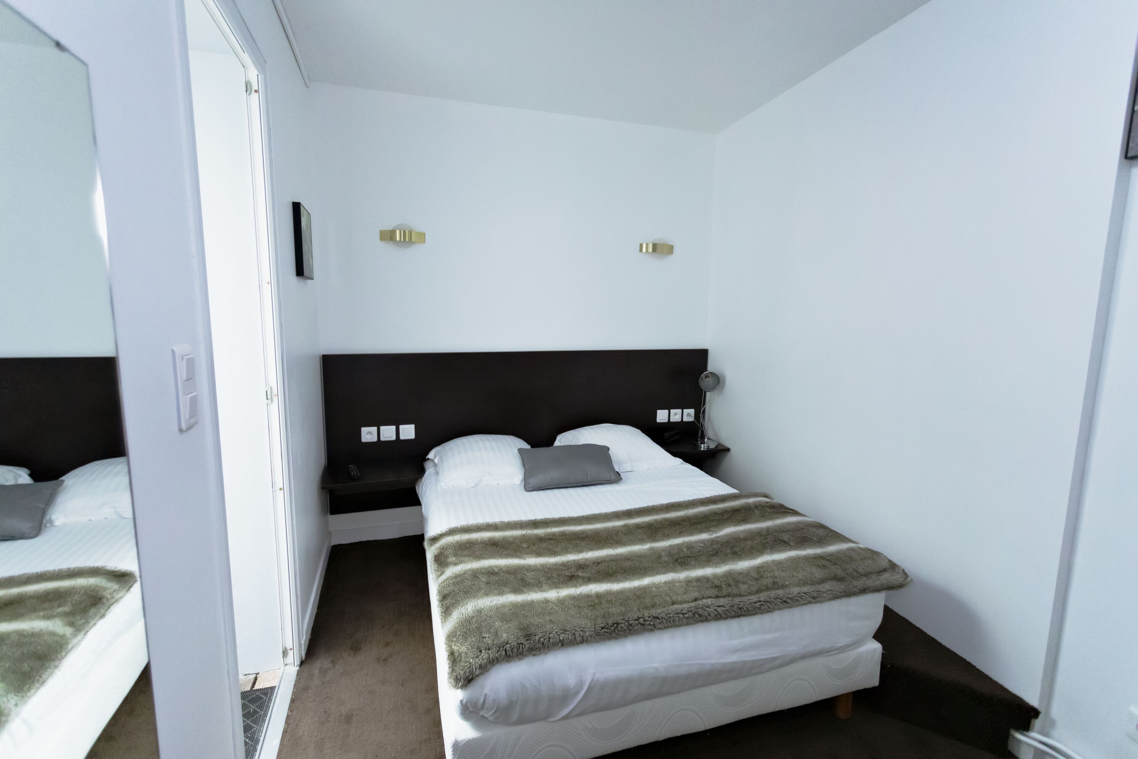 A bedroom with a bed, a nightstand, and a mirror.