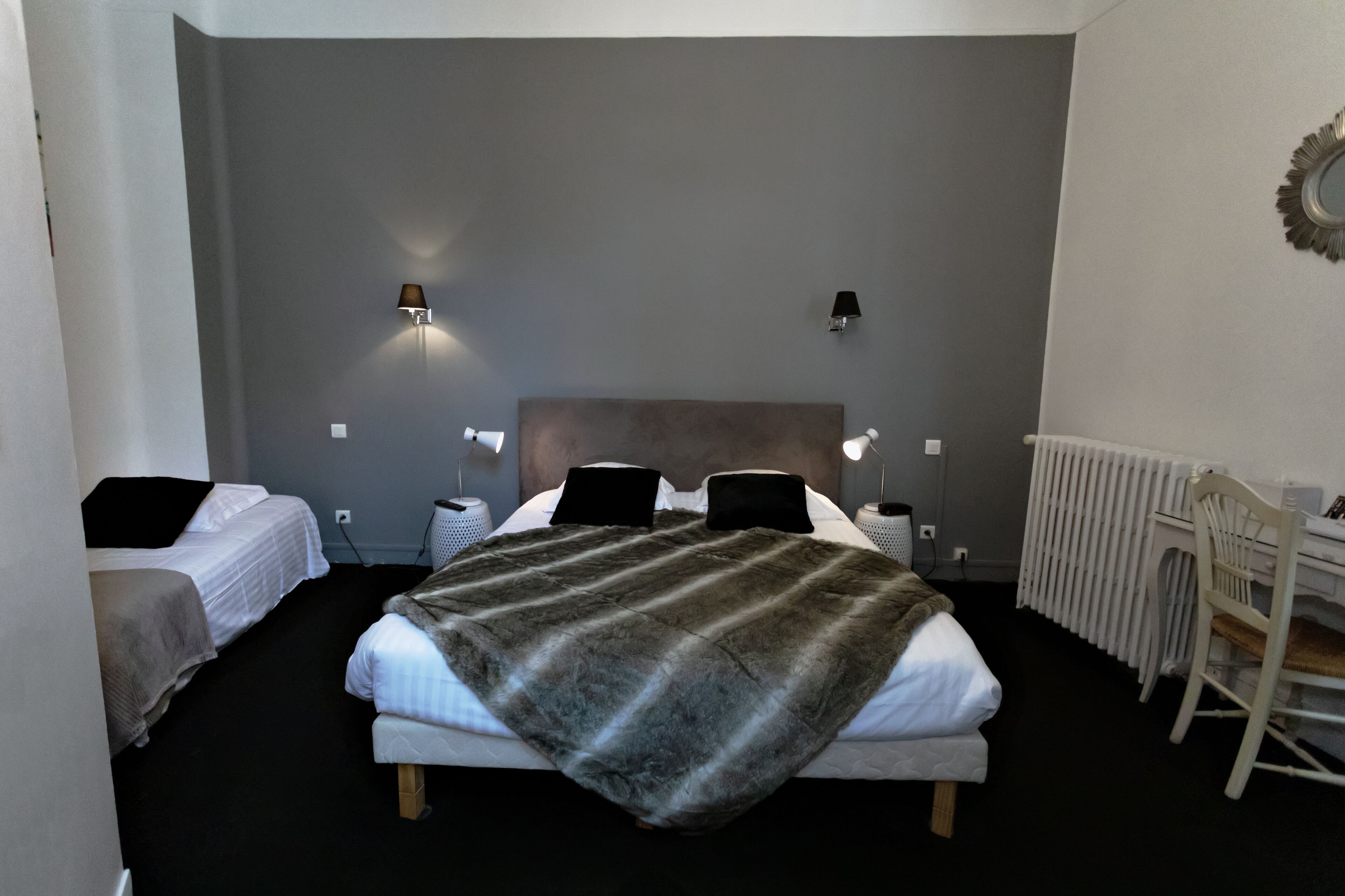 A bedroom with a large bed, two bedside tables, a chair, and a radiator.