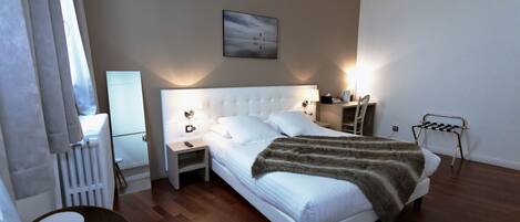Una habitación de hotel moderna con una cama grande, mesitas de noche, una silla y un radiador.