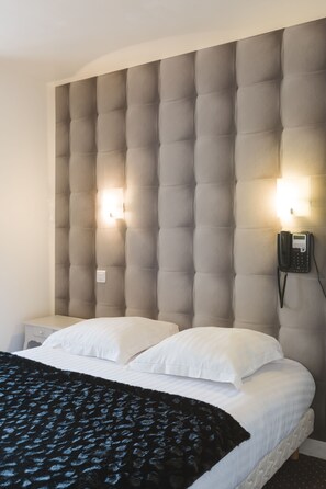 A hotel room with a tufted headboard, a bed with white linens, a black patterned throw blanket, and a bedside phone. - Hôtel Le Saint Louis (Amiens)