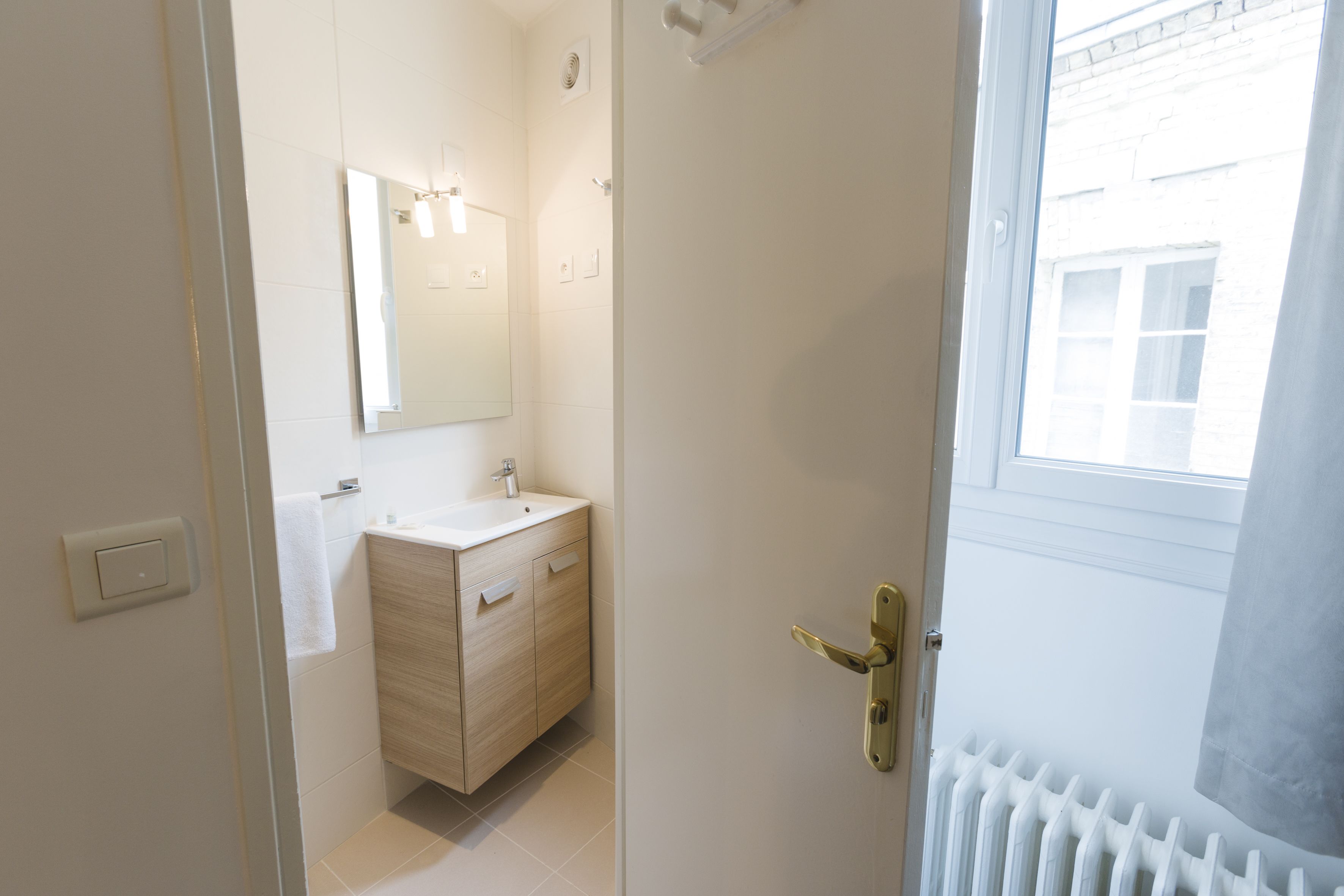 A modern bathroom with a wooden vanity, a mirror, and a radiator.