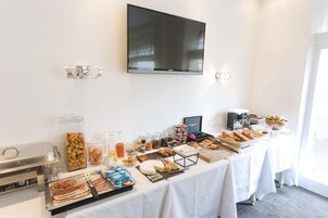 Una mesa de buffet con diferentes platillos y un televisor montado en la pared.