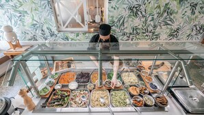 Un bufé con diversas opciones de comida y una persona sirviendo.
